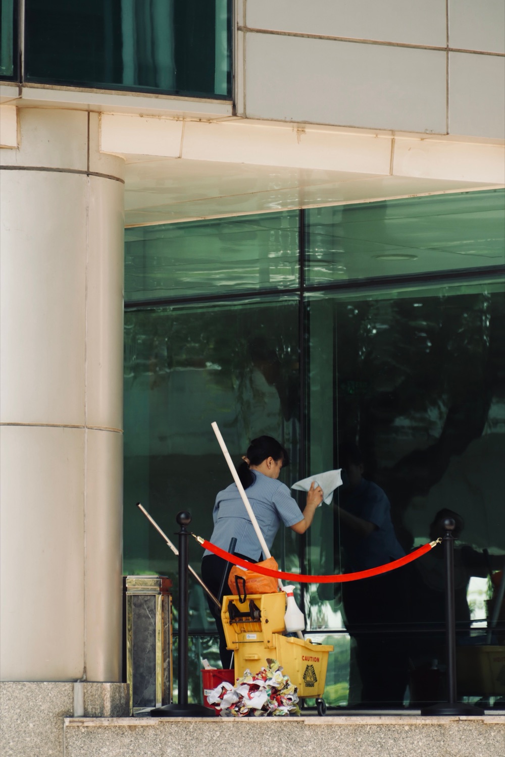 Porter cleaning lobby glass in a commercial building